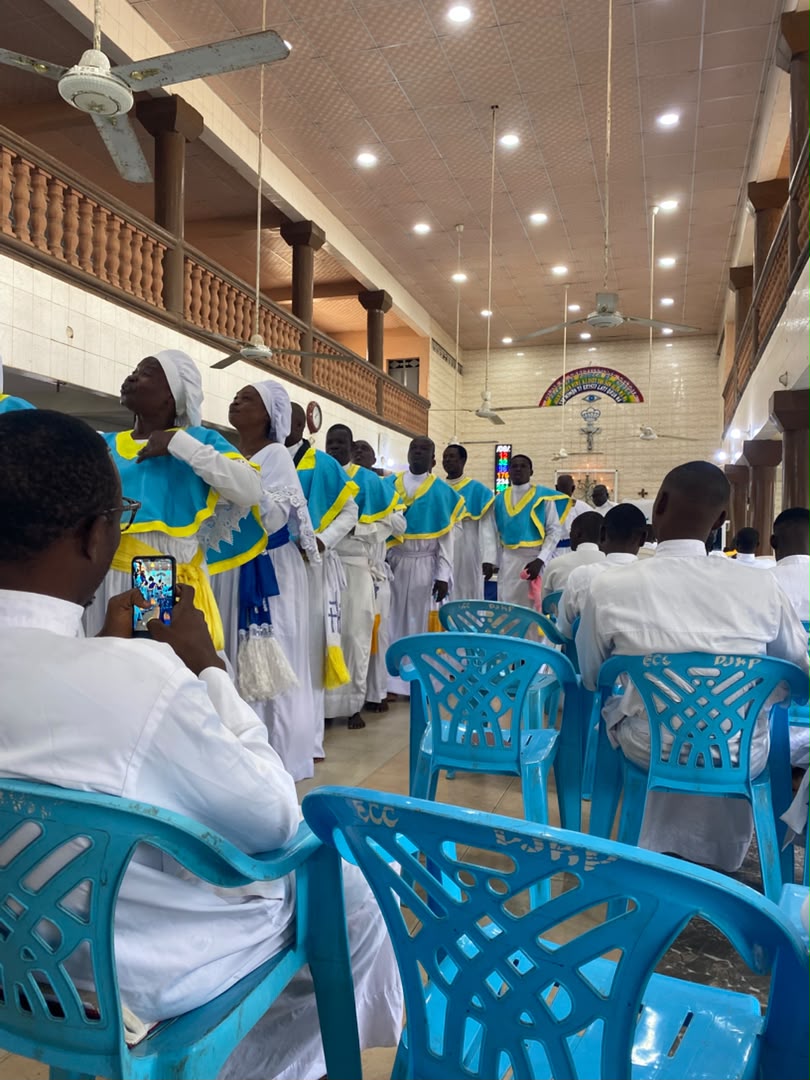 Fidèles rassemblés en habit blanc et bleu pendant un culte à la paroisse Cité d'Abraham